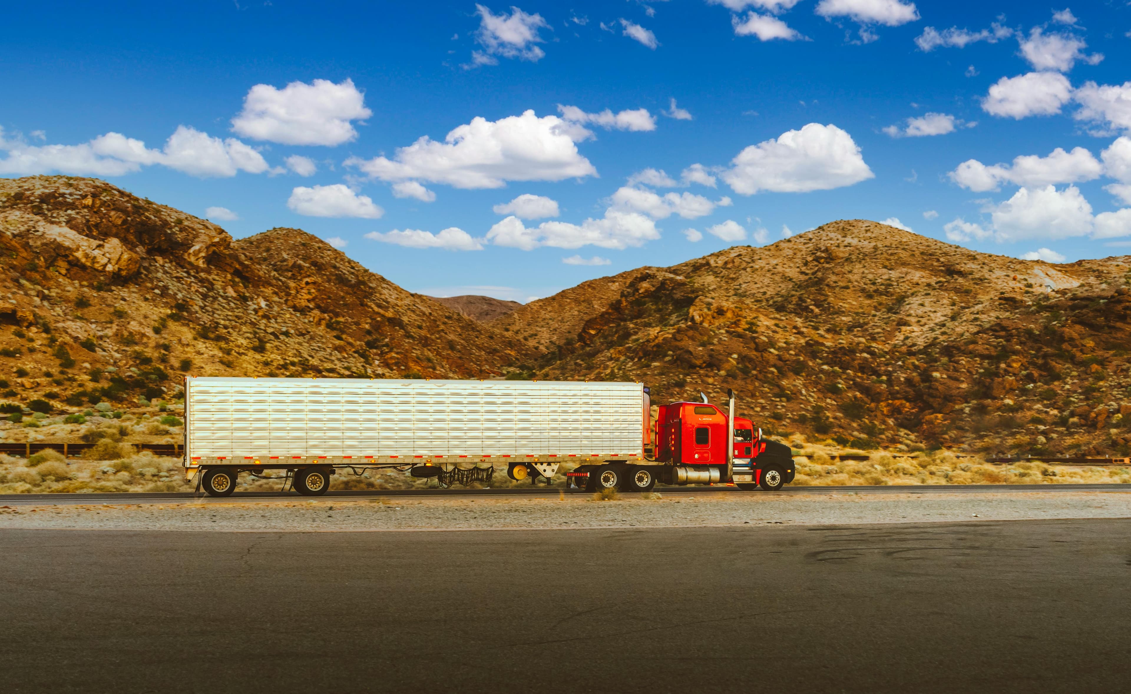 Semi truck on open highway through desert landscape
